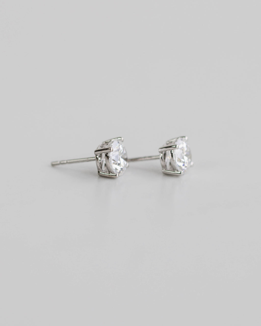 Silver stud earrings with clear gemstones on a light gray background