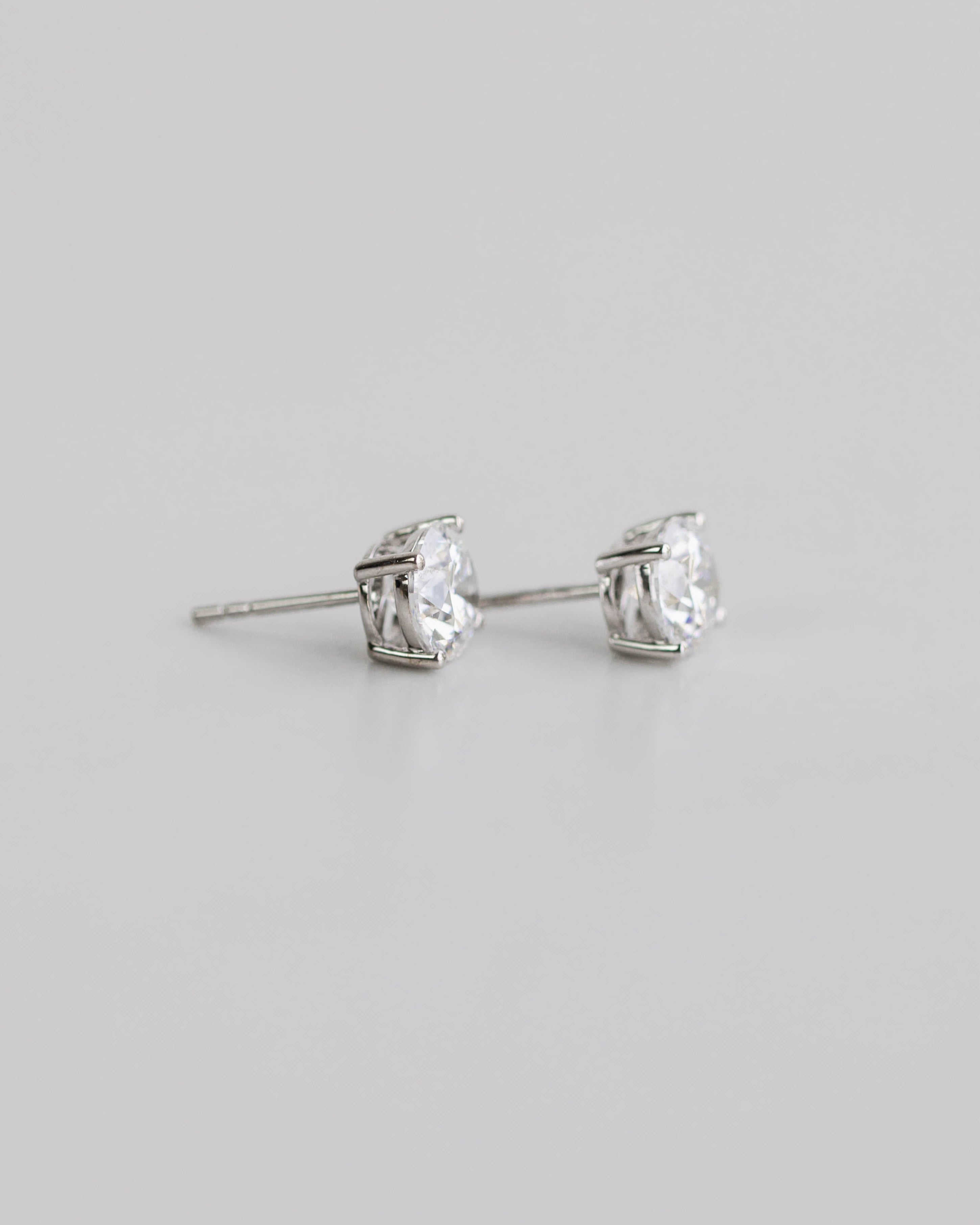 Silver stud earrings with clear gemstones on a light gray background