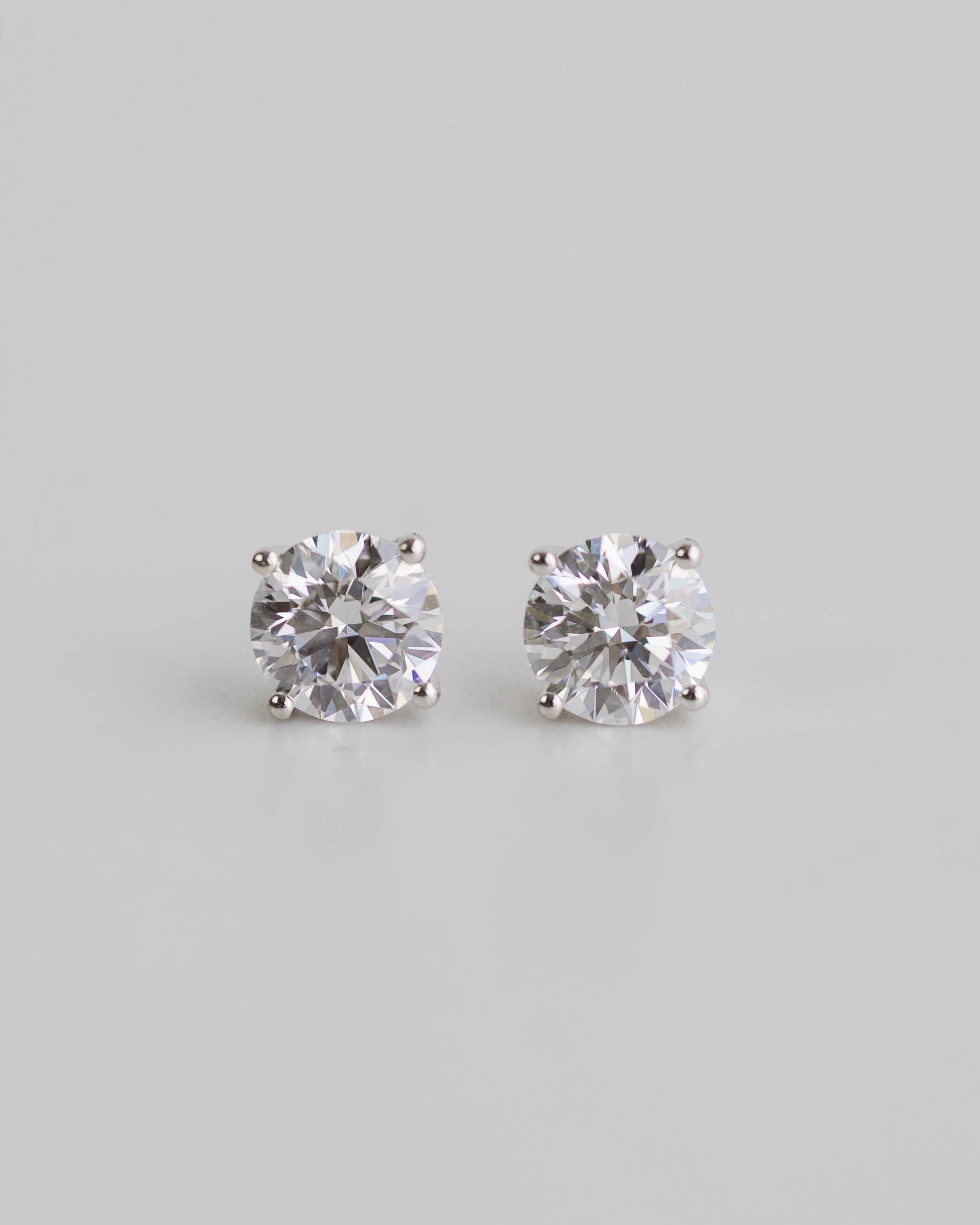 Pair of diamond stud earrings on a light gray background