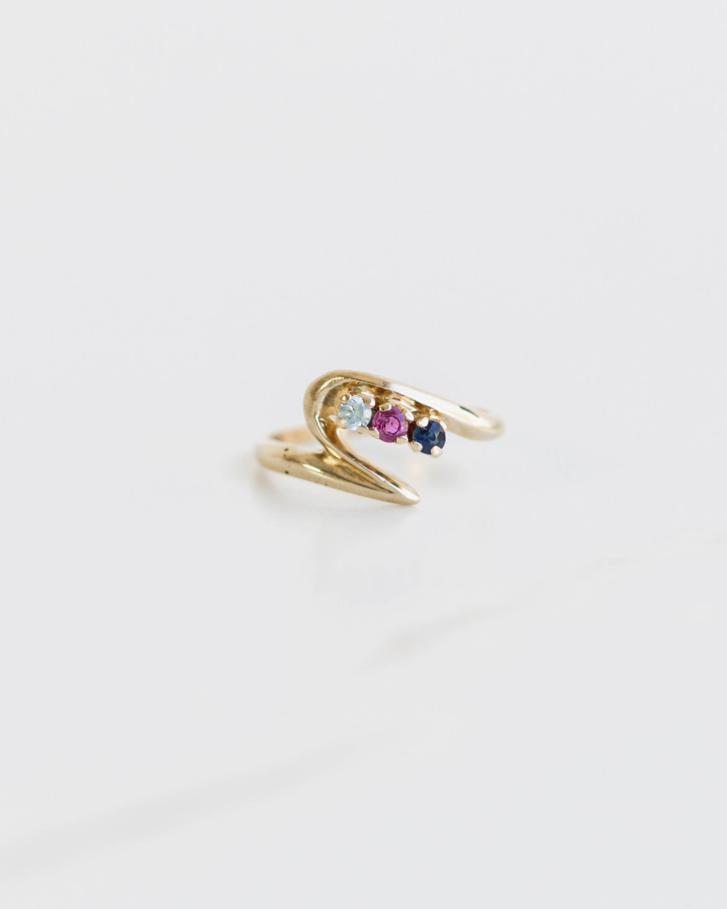 Gold ring with gemstones on a light gray background