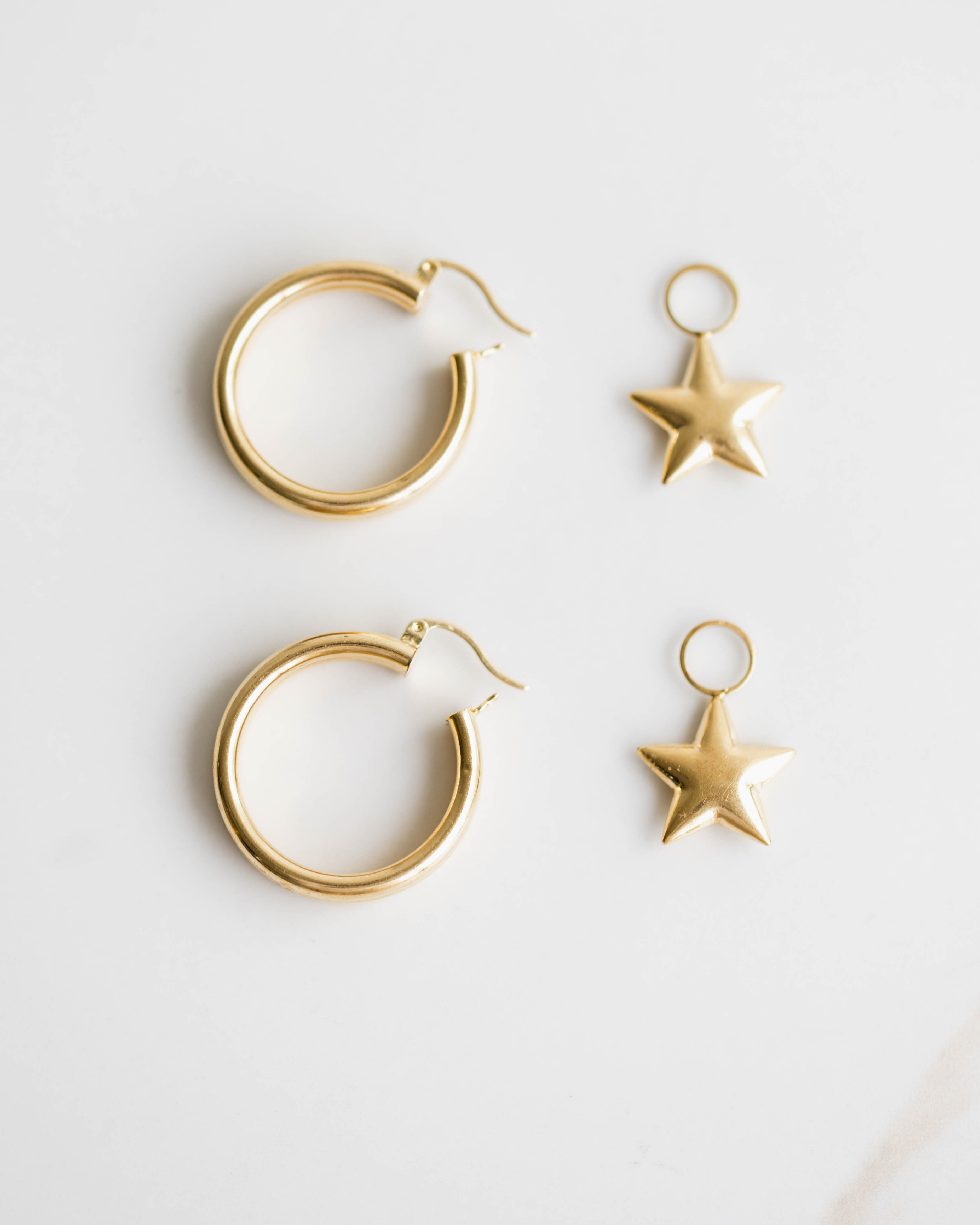 Gold hoop earrings and star-shaped pendants on a light gray background