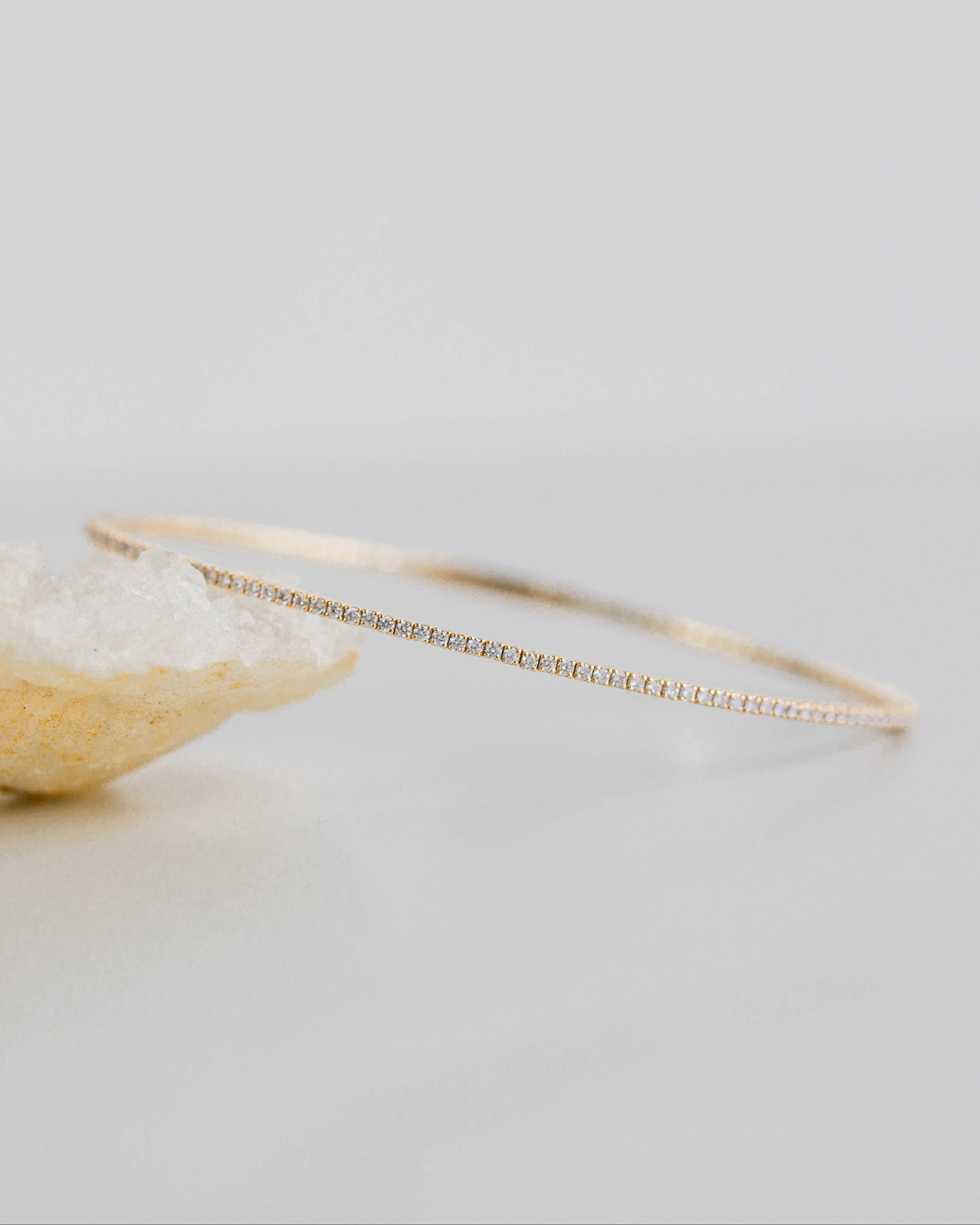 Gold hoop earring with a textured stone on a light gray background