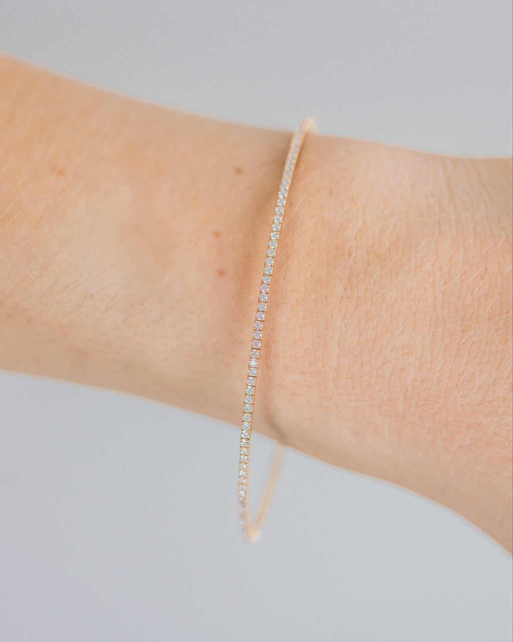 Thin bracelet on a wrist against a neutral background