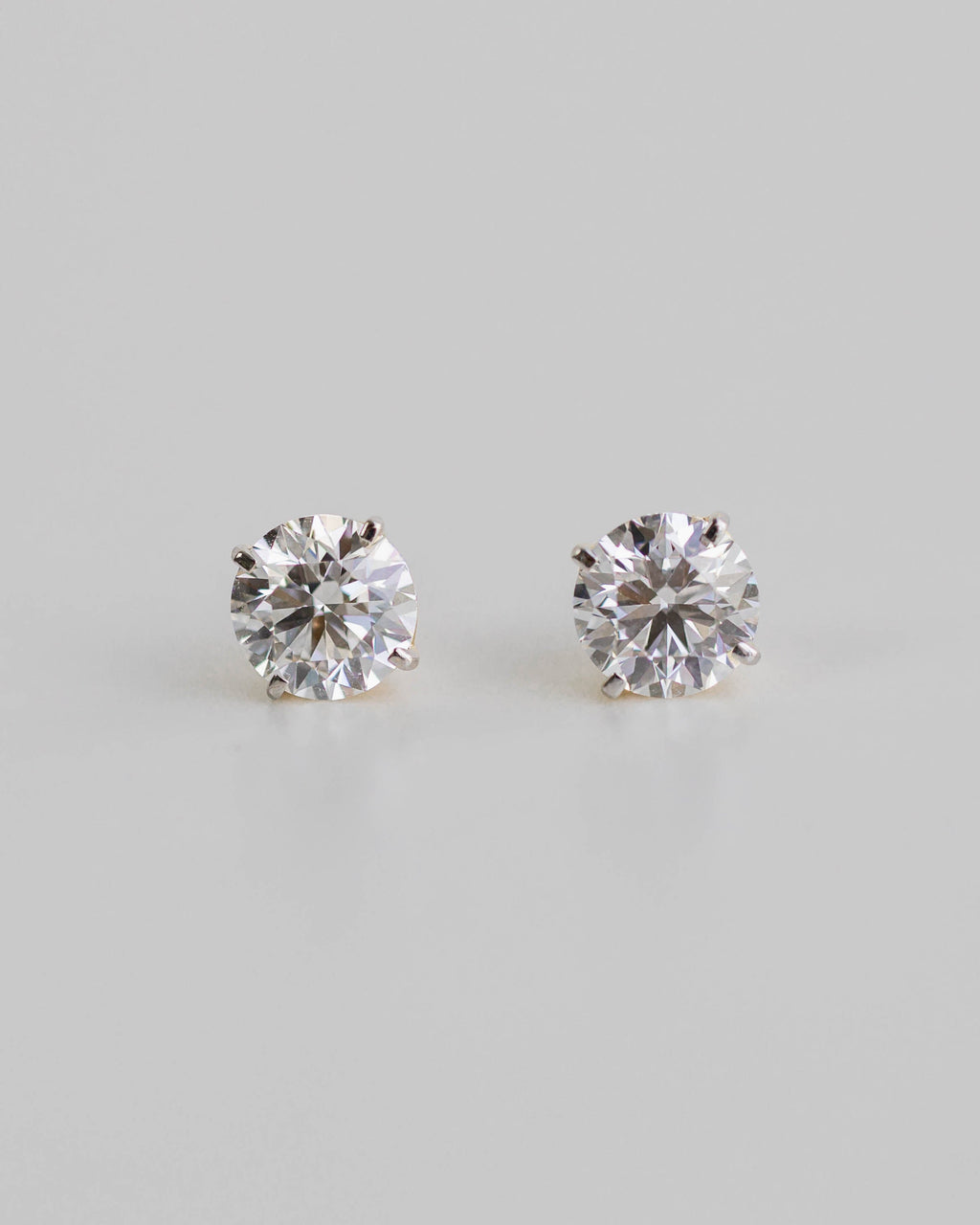 Pair of diamond stud earrings on a light gray background