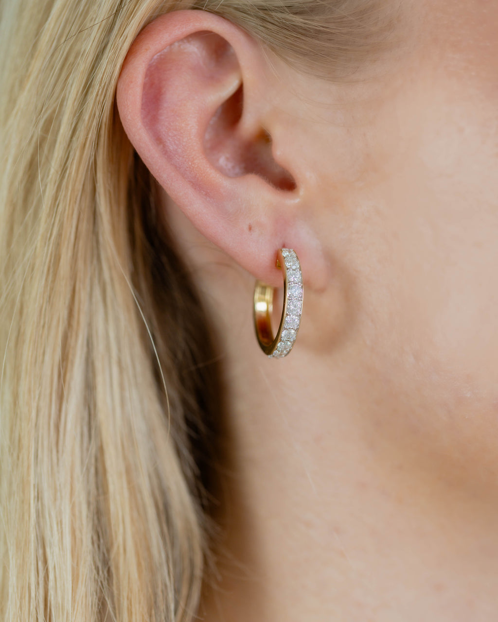Gold earring with circular design on a gray background