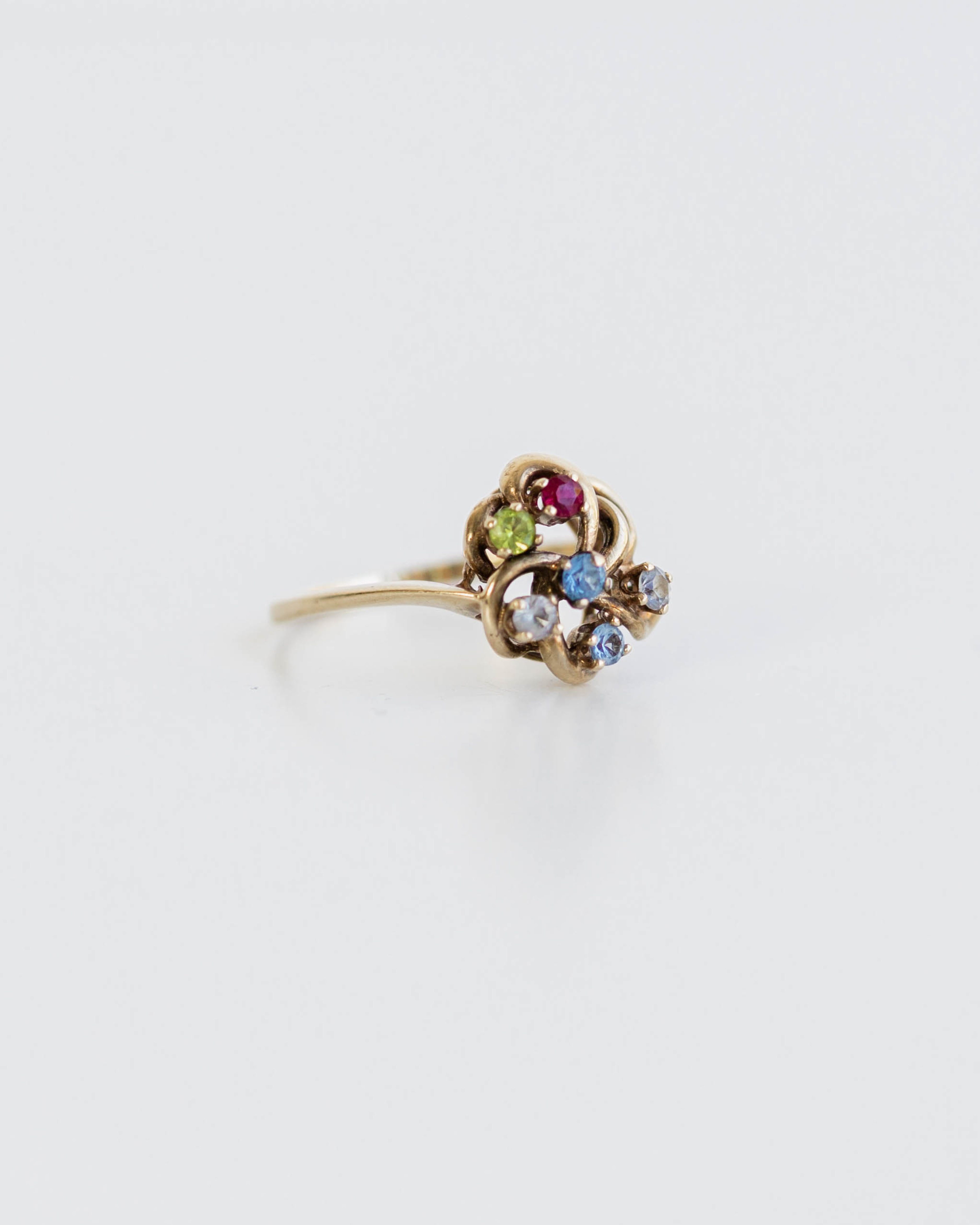 Gold ring with colorful gemstones on a light gray background