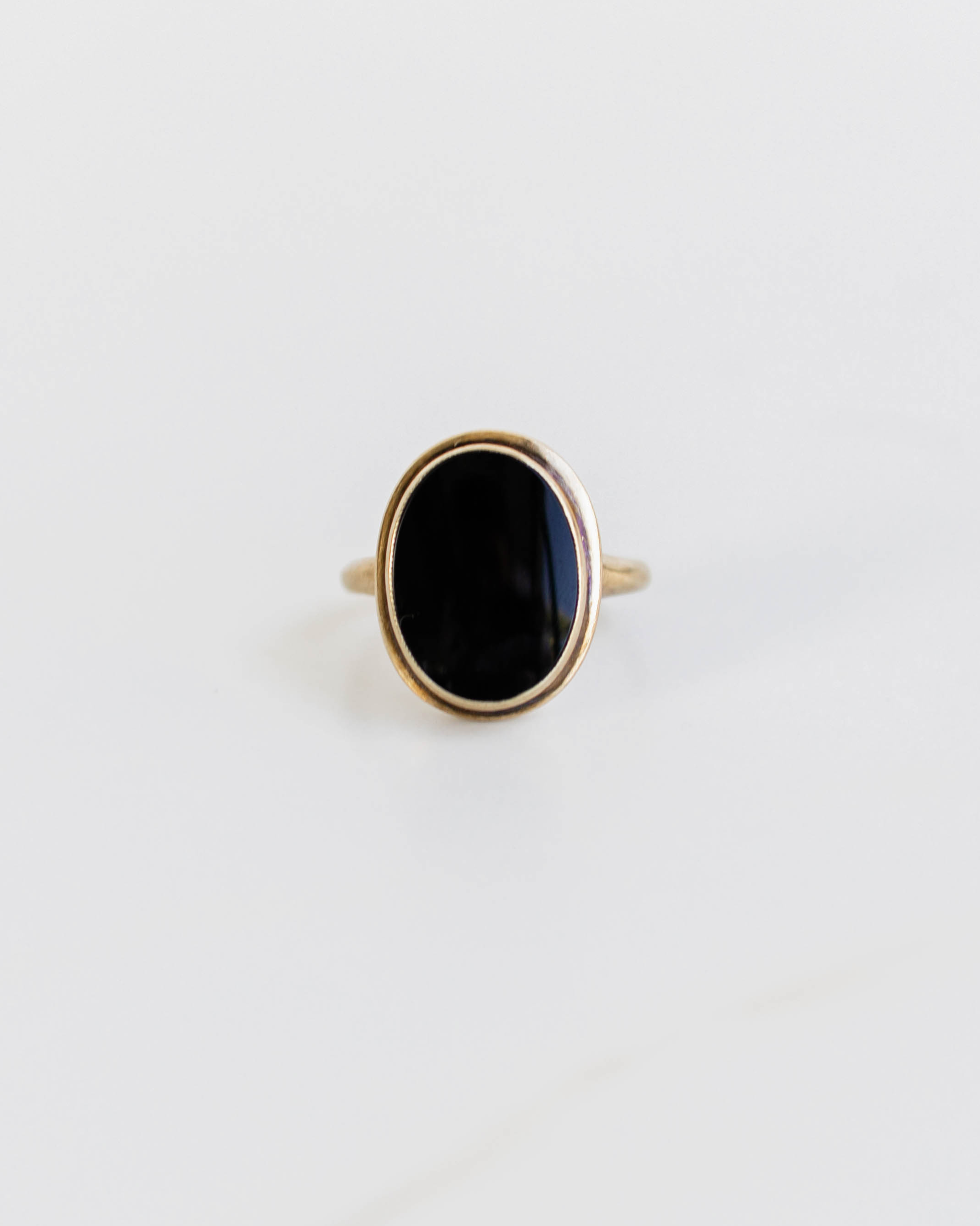 Gold ring with a black stone on a light gray background