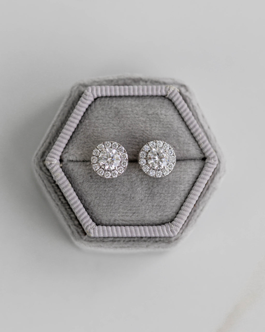 Pair of silver earrings in a hexagonal gray jewelry box on a light gray background