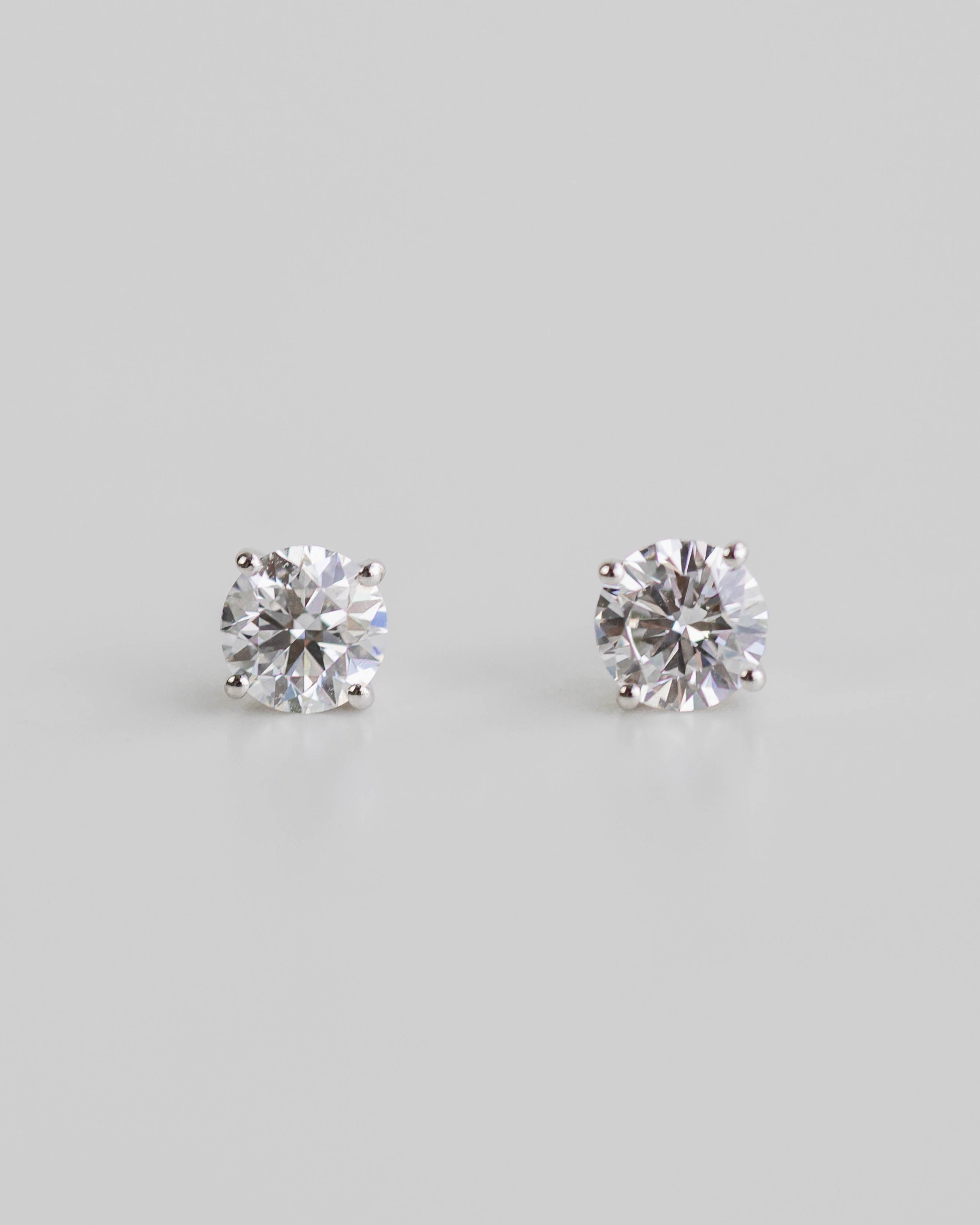Pair of diamond stud earrings on a light gray background