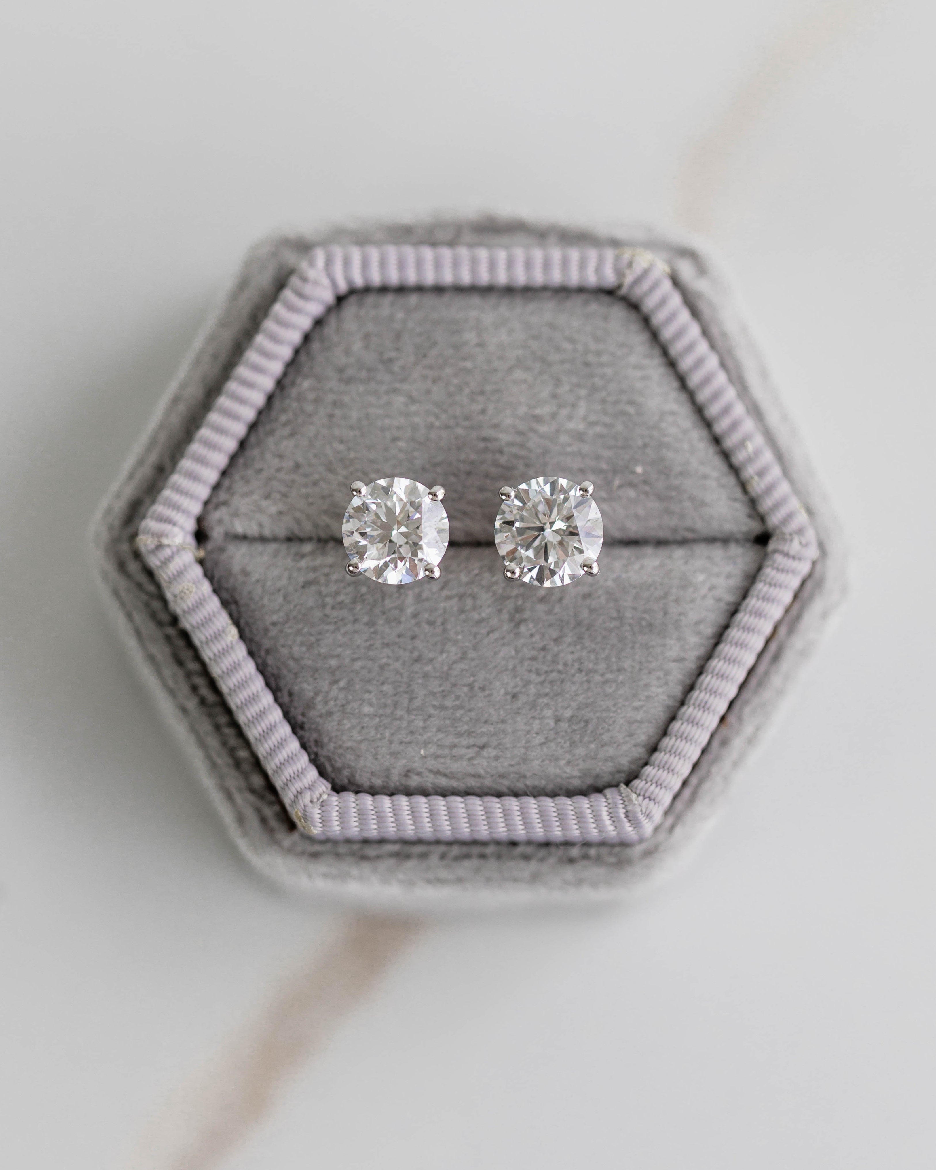 Silver stud earrings in a hexagonal gray jewelry box on a light background