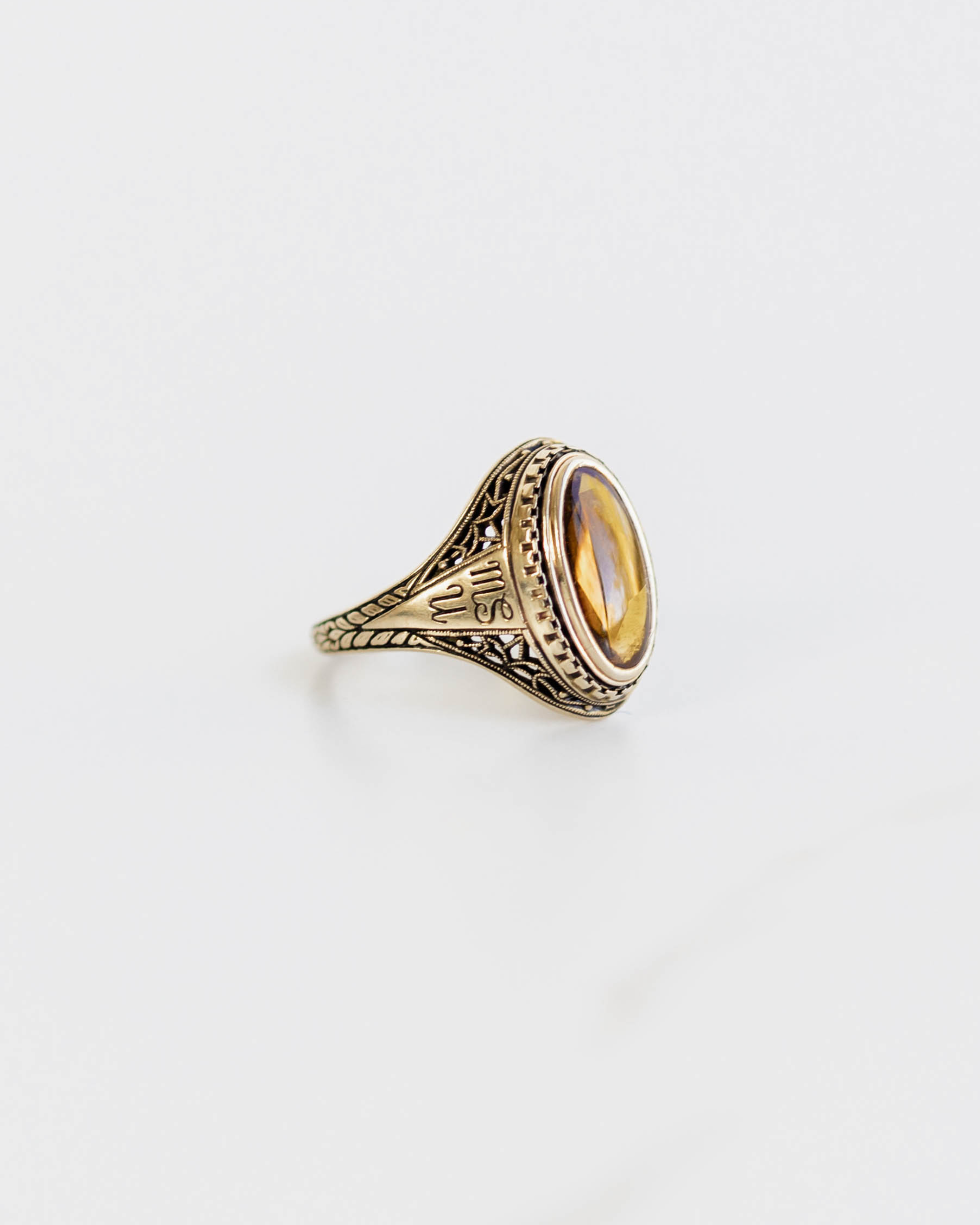 Gold ring with intricate design on a light gray background